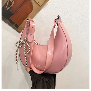 Detail of pink hobo bag with glossy finish and silver beaded bow charm accessory