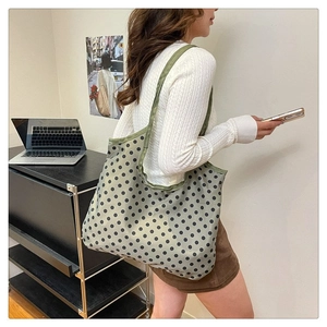 Army green polka dot canvas tote bag with wide shoulder strap shown in a lifestyle setting