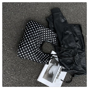 Detailed view of large black canvas hobo bag with white polka dots on asphalt road