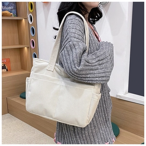 Detail of off-white corduroy tote bag showing textured fabric and side pocket design