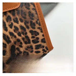 Detailed view of the leopard print fabric texture and brown leather edge on the tote bag