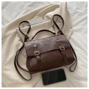 Detail of vintage brown leather backpack with metal buckle and embossed logo