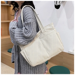 Detail view of corduroy tote bag showing side pocket and striped texture on the strap