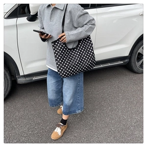 Detailed view of the black canvas tote bag with white polka dots for daily casual use