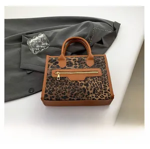 Close-up of leopard print tote bag detailing golden zipper and brown leather trim handles