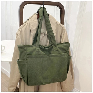 Detail of olive green corduroy tote bag with multi-pockets hanging on wooden chair