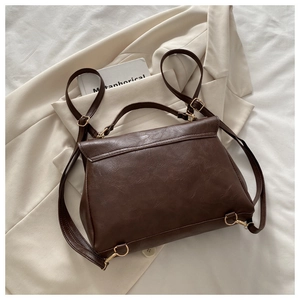Detail view of dark brown PU leather backpack with vintage lychee texture and golden hardware