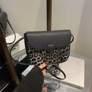 Chic leopard print and black leather saddle bag with flap closure and crossbody strap