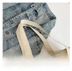 Detail shot of the wide comfortable shoulder strap on a beige nylon tote bag