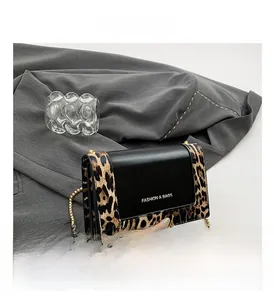 Detail of leopard print flap and gold chain strap on stylish black crossbody bag