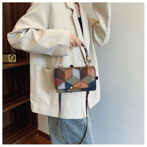 Close-up of geometric patchwork handbag with textured faux leather and gold metal buckle