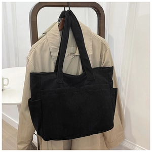 Detail of black corduroy tote bag showing side pockets and textured vertical stripes