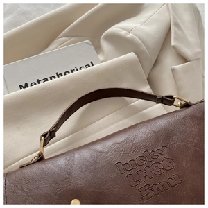 Close-up of brown textured leather backpack showing lucky LHCO Smu embossed details