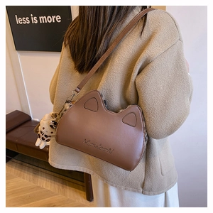 Détail d'un sac bandoulière marron aux oreilles de chat avec logo gaufré et peluche léopard