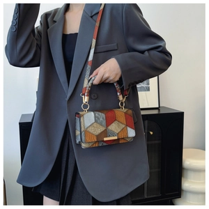 Detail view of colorful geometric patchwork texture and gold hardware on retro handbag