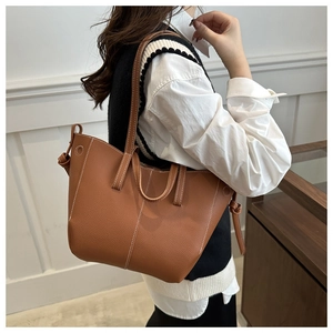Caramel brown lychee pattern tote bag with white contrast stitching on model's shoulder