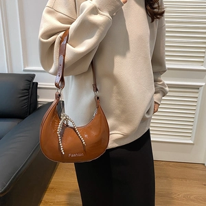 Brown vintage patent leather hobo bag with pearl tassel shown on female model