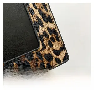 Detailed close-up of leopard print fabric and black smooth leather stitching on a small bag