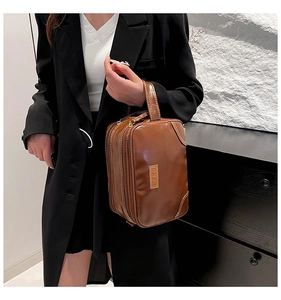 Close-up of brown vintage leather toiletry bag featuring double zipper compartments and handle