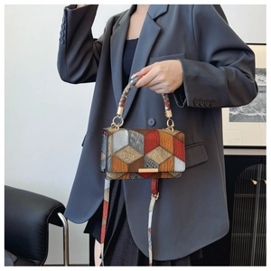 Detail of vintage geometric patchwork bag with woven handle and gold hardware shown by model