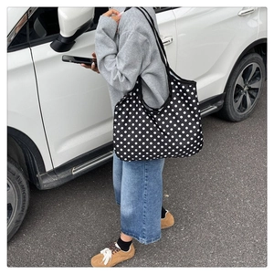 Outdoor shot of a black and white polka dot canvas tote bag with long straps