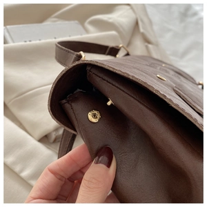 Close-up of vintage dark brown leather backpack showing metal magnetic buckle detail