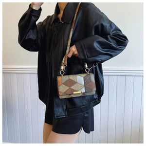 Detail shot of vintage patchwork crossbody bag with geometric patterns and gold buckle
