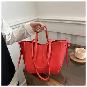 Detail of red lychee pattern leather tote bag with white stitching and carry handles