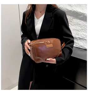 Close-up of brown vintage leather toiletry bag with LEKE logo and sturdy side handle