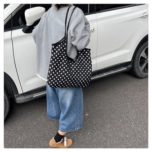Polka dot canvas tote bag with long shoulder straps shown in a lifestyle street setting