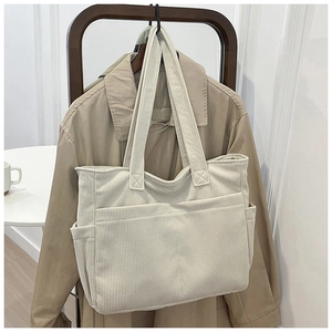 Detail of off-white corduroy tote bag showing large front pockets and ribbed texture