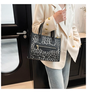 Close-up of leopard print tote bag with front zipper detail and black round handle