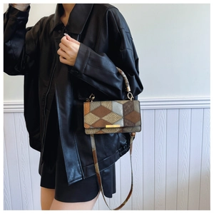 Detail of vintage patchwork crossbody bag featuring geometric patterns and gold metal bar