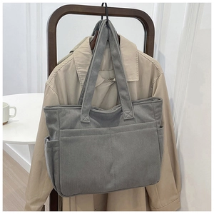 Close-up of gray corduroy tote bag hanging with beige trench coat in a home setting
