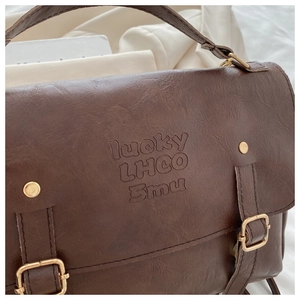 Detail of dark brown leather texture with embossed lucky lettering and gold hardware