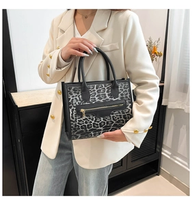 Close-up of leopard print tote bag with black leather zipper detail and sturdy top handles