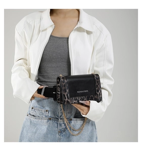 Detail of fashion crossbody bag with leopard print side and gold metal chain strap