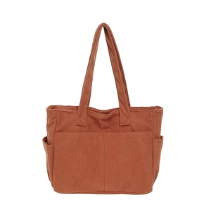 Detail view of the multi-pocket corduroy tote bag in brick red showing texture and side pockets