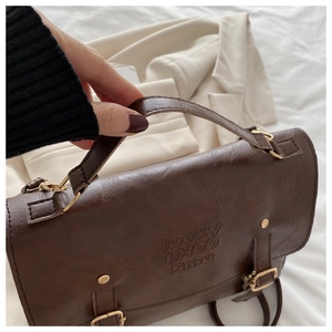 Detail of brown PU leather vintage messenger bag with lucky LHCO Smu embossed text