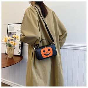 Detail of a black Halloween pumpkin crossbody bag worn with a stylish autumn trench coat