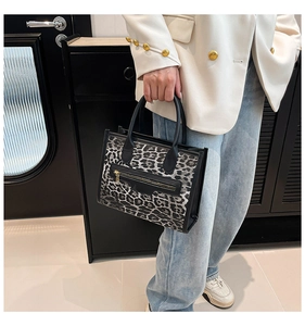 Close-up of leopard print tote bag featuring black handle and metal zipper pocket