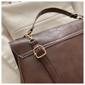 Detail of vintage brown PU leather backpack showing golden metal D-rings and strap buckles