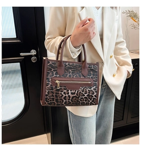 Detail view of the leopard print tote bag with brown straps and golden zipper accents