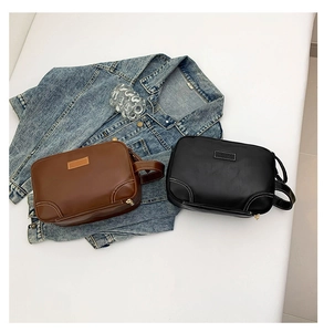 Detailed view of leather cross-body bags in brown and black with white stitching accents