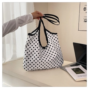 Detail of white canvas tote bag with black polka dots and durable black strap