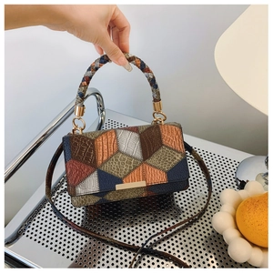 Detailed close-up of a patchwork crossbody bag with crocodile texture and woven handle