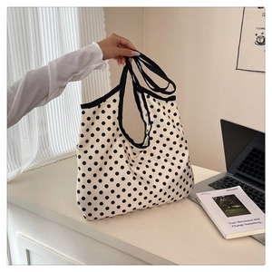 Close-up of black polka dot canvas tote bag with reinforced handles in a lifestyle setting