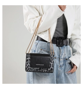 Detail of grey leopard print and black leather crossbody bag with golden chain strap