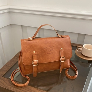 Detail of vintage brown PU leather backpack with gold buckles on a wooden surface