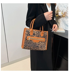 Detail of leopard print tote bag with brown leather handles and a front zipper pocket